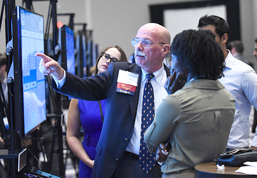 Image of a group of students being judged by a Poster Symposium judge