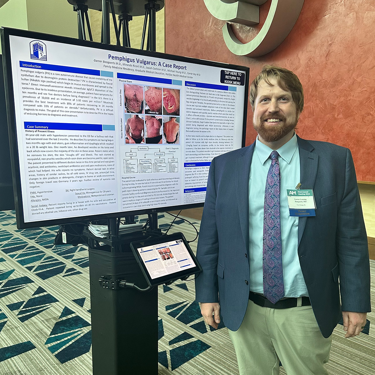 Garner Boogaerts, MD stands with his winning poster