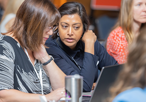 Two female physicians look at a computer screen