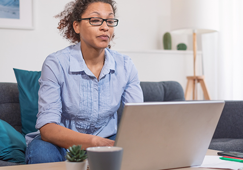 Female sitting on a desk with a computer. 